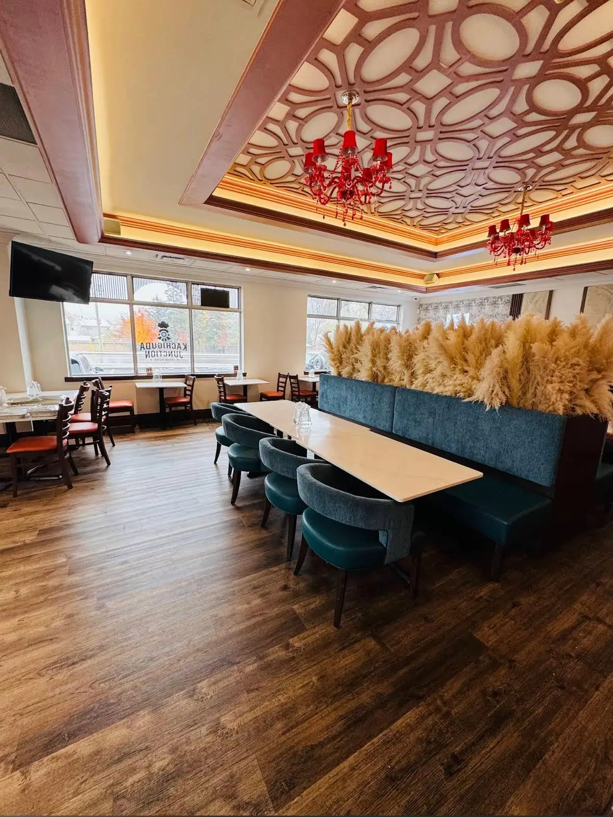 Red glass chandeliers hanging from a carved fretwork ceiling above the long communal table in the dining room