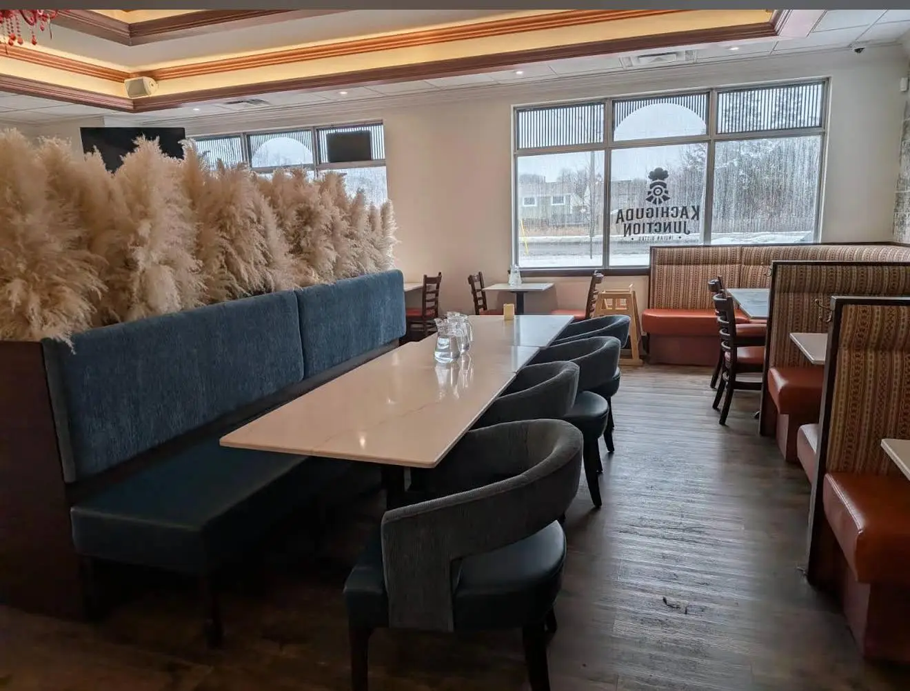 The marble communal table with its blue banquette and pampas grass screen, beside windows onto a snowy Whitby street