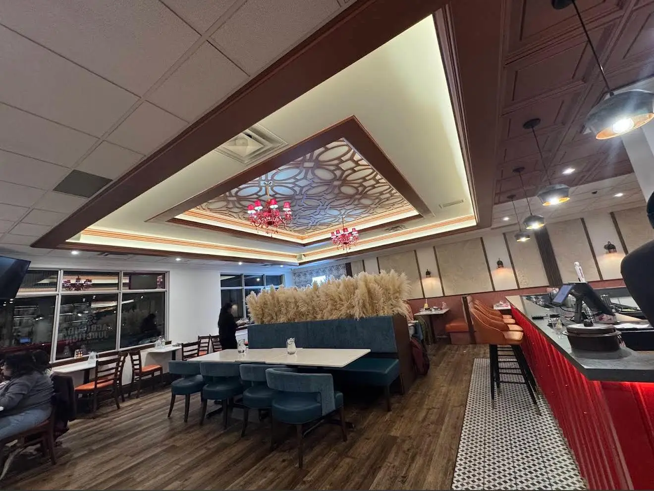 The dining room in the evening, looking past the booths to the red bar counter beneath the lit fretwork ceiling