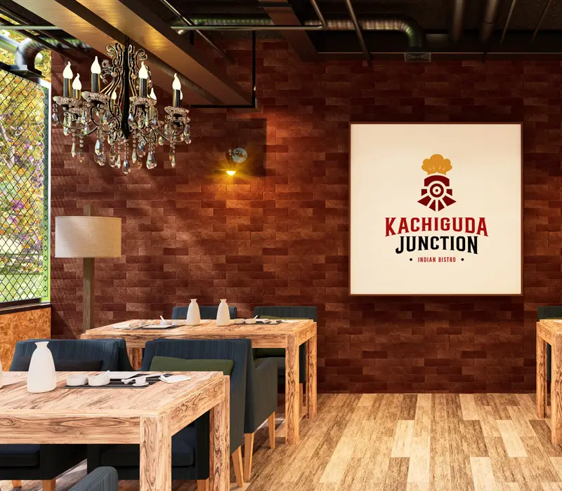 The dining room at Kachiguda Junction — timber tables and benches under a chandelier, with the restaurant's logo on the brick wall